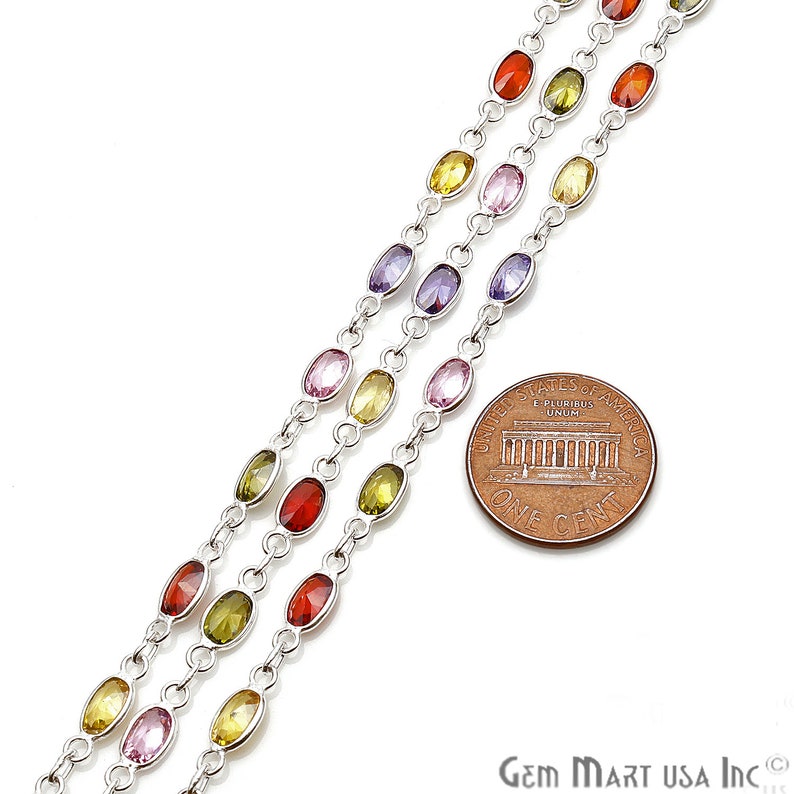 May include: Three strands of silver chain with oval-shaped gemstones in various colors, including red, orange, yellow, green, purple, and pink. The chain is next to a US penny for scale.