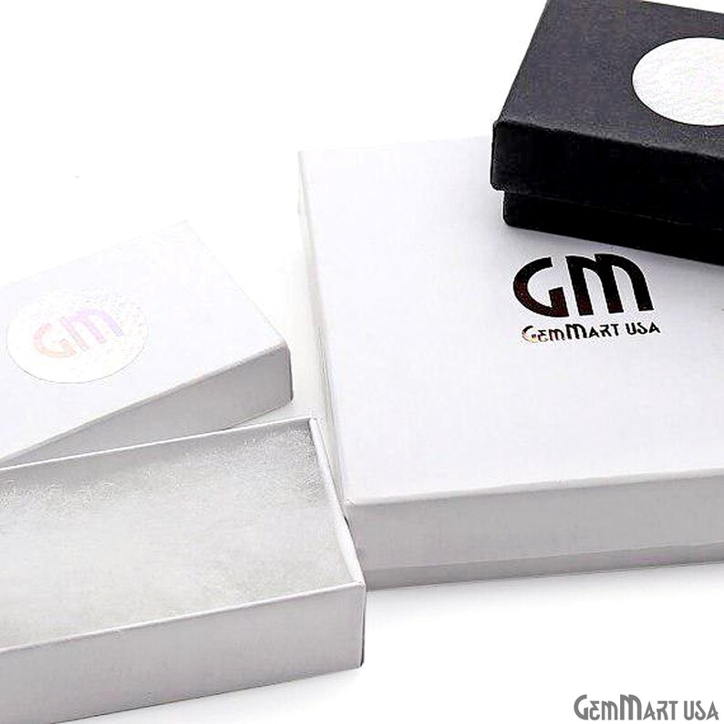 K&ouml;nnte beinhalten: Eine Sammlung wei&szlig;er und schwarzer Schmuckschatullen. Die rechteckigen Schachteln tragen das Logo "GM" und "GemMart USA". Eine Schachtel ist ge&ouml;ffnet und zeigt einen wei&szlig;en Innenraum.