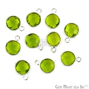 Peut inclure: Dix pendentifs en pierre précieuse verte avec des boucles d'attache en argent. Chaque pendentif est rond et a une surface facetée.