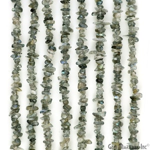May include: A strand of gray and iridescent labradorite chip beads. The beads are irregular in shape and size, and they have a natural, rough finish. The beads are strung on a clear thread and are ready to be used for jewelry making.