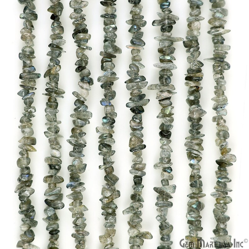 May include: A strand of gray and iridescent labradorite chip beads. The beads are irregular in shape and size, and they have a natural, rough finish. The beads are strung on a clear thread and are ready to be used for jewelry making.