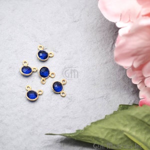 May include: Six gold-toned metal connector charms with blue faceted glass stones. Each charm has two loops for attaching to jewellery.