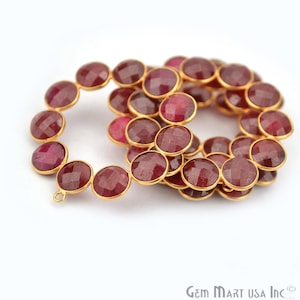 May include: A strand of ruby red gemstone beads with gold-toned accents. The beads are round and faceted, and they are strung on a gold-toned wire. The strand is approximately 18 inches long.