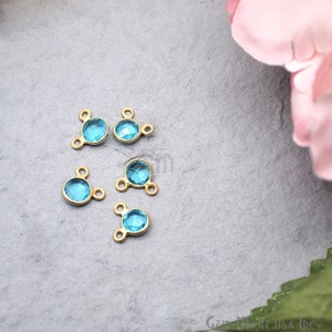 May include: Five gold-tone metal connector charms with a light blue round gemstone in the centre. Each charm has three loops for attaching jewellery.