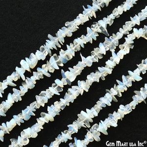 May include: A strand of white and blue opal chip beads. The chips are irregular in shape and have a translucent appearance. The beads are strung on a clear thread and are arranged in a staggered pattern.