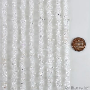 May include: A strand of clear quartz chip beads, approximately 16 inches long. The beads are irregular in shape and size, with some being very small. The beads are strung on a clear elastic cord. The beads are shown next to a US penny for scale.