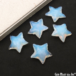 May include: Five opalescent star-shaped gemstones with a light blue and white color scheme. The gemstones have a rough, textured edge and are arranged on a black surface. The gemstones are likely for jewelry making or crafting.