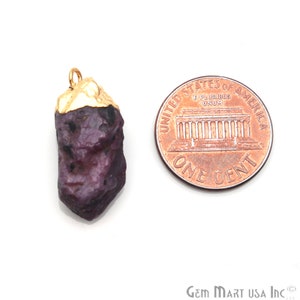 May include: A dark purple, rough-cut gemstone pendant with a gold-plated top. The pendant is about the size of a US penny.