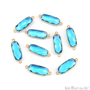 Peut inclure: Huit connecteurs rectangulaires en verre bleu aux surfaces facettées, chacun enchâssé dans un cadre en métal doré. Chaque pièce présente deux petites boucles circulaires, une à chaque extrémité, conçues pour l'assemblage de bijoux.