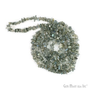 May include: A strand of grey and blue labradorite gemstone chips. The chips are irregular in shape and have a shimmery, iridescent finish.