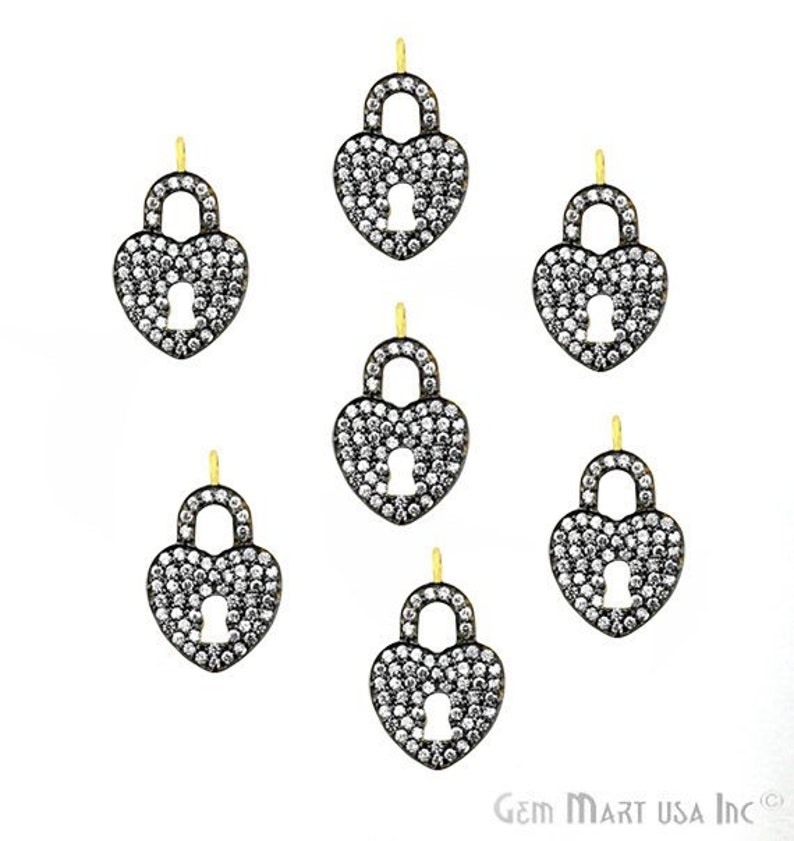 May include: Six gold-tone lock and key charm pendants with pave-set clear cubic zirconia stones. Each pendant is shaped like a heart with a lock and key design.