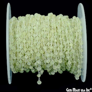 May include: A spool of silver chain with light green gemstone beads. The chain is made of small, round beads that are strung together with silver wire. The chain is about 18 inches long and is perfect for making jewelry.