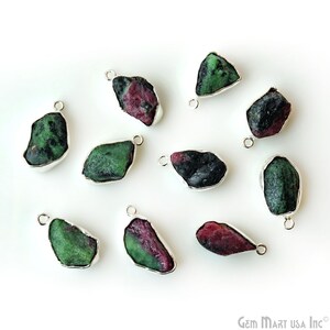 May include: Ten raw, rough, green and pink gemstone pendants with silver bail settings. The gemstones are in various shapes and sizes.