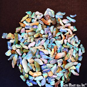 May include: A collection of iridescent opal chips in various shapes and sizes. The chips are a mix of blue, green, and white colors.