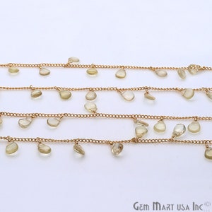 May include: A gold chain with teardrop-shaped clear quartz gemstone accents. The chain is layered and has multiple strands.