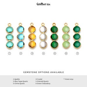 May include: Seven vertical gold-tone pendants, each featuring three faceted gemstones in various colors. The text GEMMART USA appears at the top, and GEMSTONE OPTIONS AVAILABLE with a numbered list of stones 1 through 7 is at the bottom.