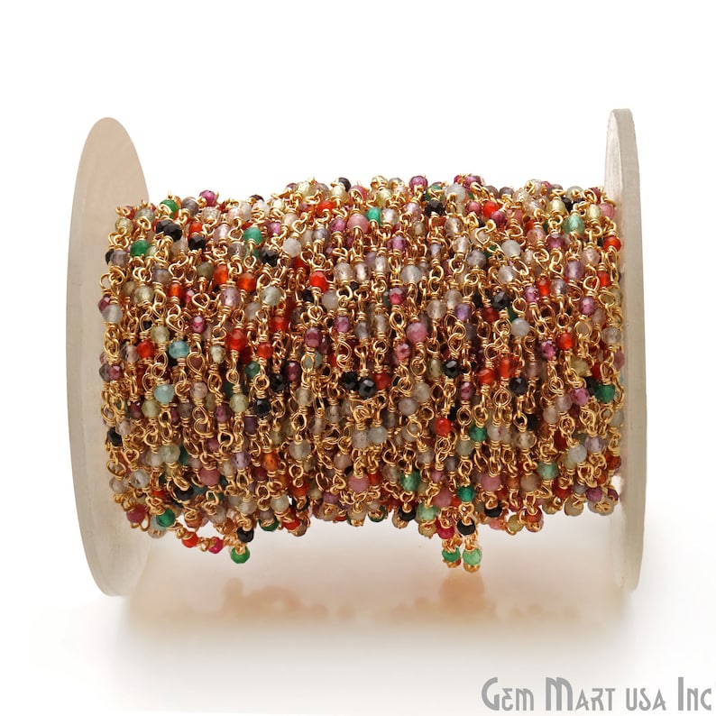 May include: A spool of gold chain with small, colorful gemstone beads. The chain is made of gold-plated metal and the beads are a mix of red, green, blue, and purple.