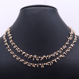 May include: A double-strand necklace with small white and gray beads. The necklace has a delicate, feminine look and is perfect for adding a touch of elegance to any outfit.