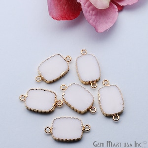 May include: Six white rectangular connector charms with gold-toned edges and two jump rings. The charms are on a white surface.