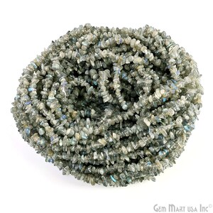 May include: A strand of gray and iridescent labradorite chip beads. The beads are irregular in shape and have a natural, rough texture.