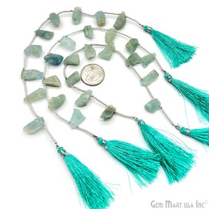May include: A strand of light blue aquamarine gemstone beads with silver spacers and turquoise tassels. The beads are irregular in shape and size. A US quarter is included for scale.