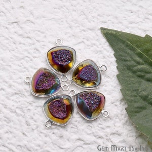 Könnte beinhalten: Fünf regenbogenfarbene dreieckige Edelstein-Anhänger mit silberfarbenen Sprungringen. Die Edelsteine haben eine glitzernde, gesprenkelte Textur und eine Mischung aus violetten, goldenen und braunen Farbtönen.