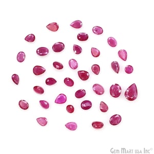 May include: A collection of loose, polished ruby gemstones in various shapes and sizes, including oval, pear, and round cuts. The rubies display a range of pink to deep red hues, scattered on a white background.