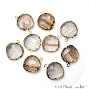 May include: Ten gold-toned gemstone pendants with a faceted, rounded square shape. The gemstones are clear with a subtle shimmer and some have brown and gold streaks.