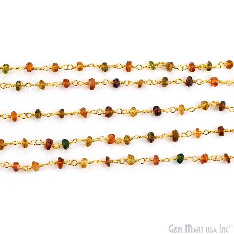 May include: A gold-toned wire-wrapped chain featuring small, irregular, multi-coloured gemstone beads in shades of amber, brown, and green. The chain is arranged in five horizontal rows, showcasing a delicate link design with evenly spaced stones.