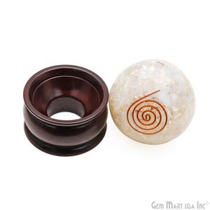 May include: A white crystal sphere with a copper wire spiral design, resting on a dark brown wooden stand.