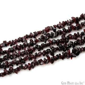 May include: A strand of dark red gemstone chips, likely garnet, arranged in a loose, flowing pattern. The chips are irregular in shape and size, creating a natural and organic look.