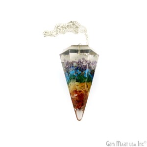 Puede incluir: Un péndulo de cristal transparente con una cadena plateada. El péndulo está lleno de siete capas de cristales de diferentes colores, que representan los siete chakras. Los cristales están dispuestos en un patrón de arcoíris, comenzando con rojo en la parte inferior y terminando con violeta en la parte superior.