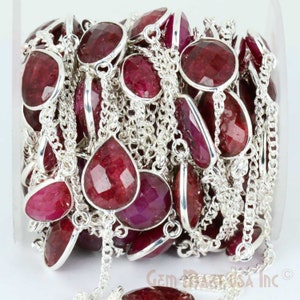 May include: A strand of ruby gemstone beads with silver chain links. The beads are faceted and have a deep red color. The chain is silver and has a delicate design.