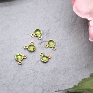 May include: Five gold-toned metal connector charms with green gemstone accents. Each charm has three loops for attaching jewellery.