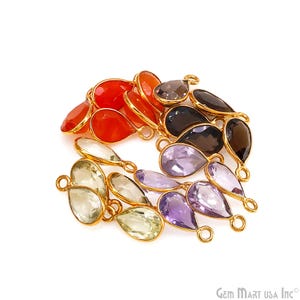 May include: A collection of teardrop-shaped gemstone pendants in various colors, including red, purple, green, and black. Each gem is set in a gold-colored metal frame with a small loop for attaching to jewelry.