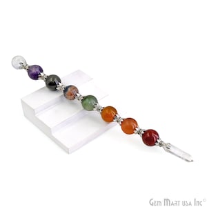 May include: A gemstone wand featuring a clear quartz crystal point and a series of colorful, round gemstones. The gemstones are connected by silver-colored metal accents. The wand is designed with a variety of colors, including purple, green, orange, and red.