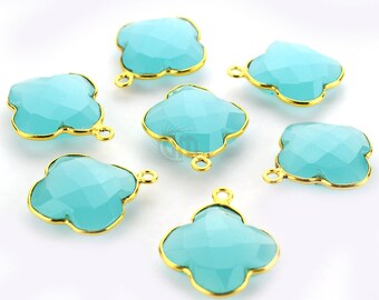 May include: Seven turquoise blue gemstone charms with gold-toned metal frames in a clover shape. Each charm has a loop for attaching to jewelry.