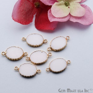 May include: Six white oval-shaped pendant charms with gold-toned edges and two jump rings. The charms are on a white surface.