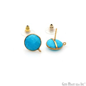 May include: Two gold-colored stud earrings with bright turquoise-colored stones. The stones are round and oval-shaped, set in gold-colored metal. The earrings have clear plastic backings and are displayed on a white background.