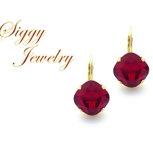 Könnte beinhalten: Ein Paar goldene Ohrringe mit roten Kristallsteinen. Die Ohrringe haben ein schlichtes Design und sind perfekt für den Alltag.