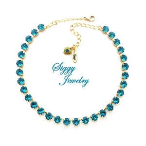 K&ouml;nnte beinhalten: Eine goldene Kettenkette mit einer Reihe von t&uuml;rkisblauen Kristallen. Die Kette hat einen herzf&ouml;rmigen Anh&auml;nger mit dem Text "Siggy Jewelry".