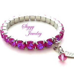 Peut inclure: Un bracelet extensible avec une rangée de cristaux roses et un petit charme avec l'inscription "Siggy Jewelry".