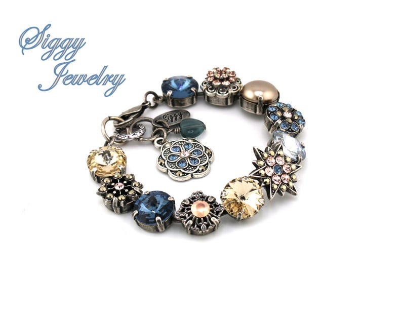 May include: A silver charm bracelet with a variety of colorful crystal charms, including blue, pink, and gold. The charms are in the shape of flowers, stars, and other geometric designs.