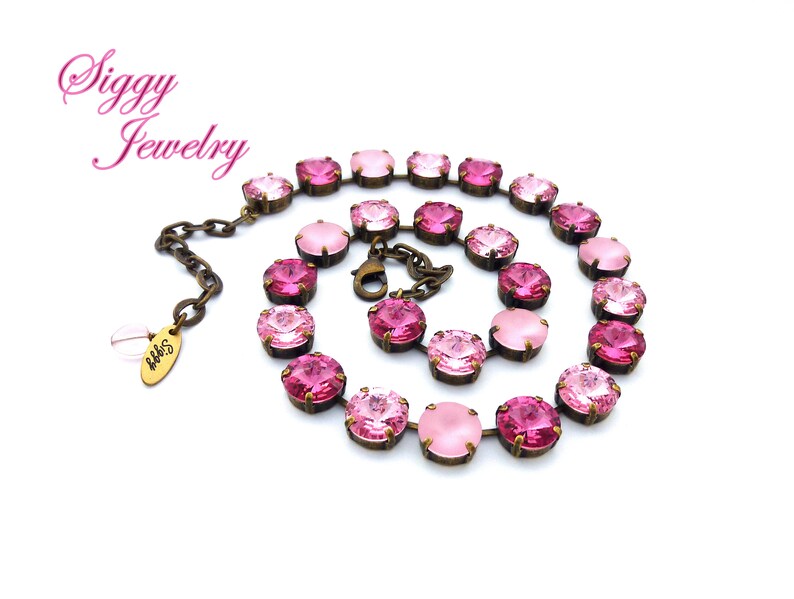 Pode incluir: Um colar rosa e dourado rosa com um efeito degrad&ecirc;. O colar &eacute; feito com contas de cristal facetadas e uma corrente de lat&atilde;o.