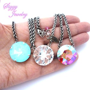 May include: Three silver chain necklaces with round crystal pendants. The pendants are in shades of blue, clear, and pink.