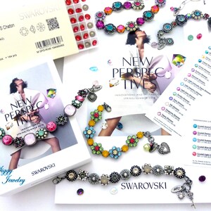 May include: A close-up of three colorful bracelets with flower-shaped charms. The bracelets are made of metal and feature crystals in various colors, including pink, blue, green, and yellow. The bracelets are arranged on a white surface with a brochure for Swarovski crystals.