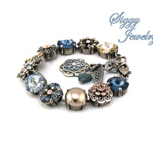 May include: A silver bracelet with blue, pink, and gold flower-shaped charms. The bracelet has a pearl charm and a charm with the text "Siggy Jewelry".