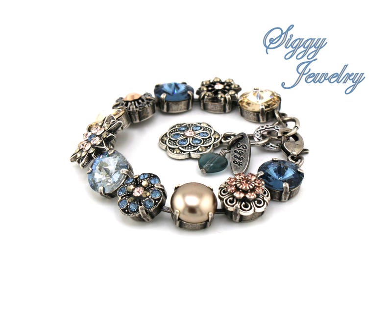 May include: A silver bracelet with blue, pink, and gold flower-shaped charms. The bracelet has a pearl charm and a charm with the text "Siggy Jewelry".