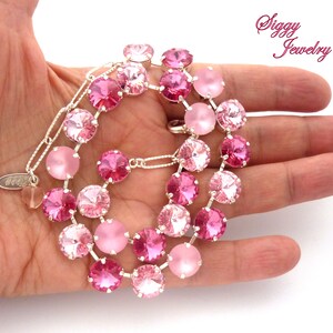 Pode incluir: Um colar de cristal rosa com uma corrente de prata. O colar apresenta um degrad&ecirc; de cristais rosa, com os cristais rosa mais claros na parte superior e os cristais rosa mais escuros na parte inferior. O colar est&aacute; em uma m&atilde;o, e o texto "Siggy Jewelry" &eacute; vis&iacute;vel no fundo.