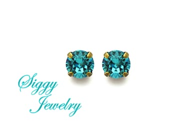May include: A pair of small, round earrings with turquoise blue crystals and gold settings.
